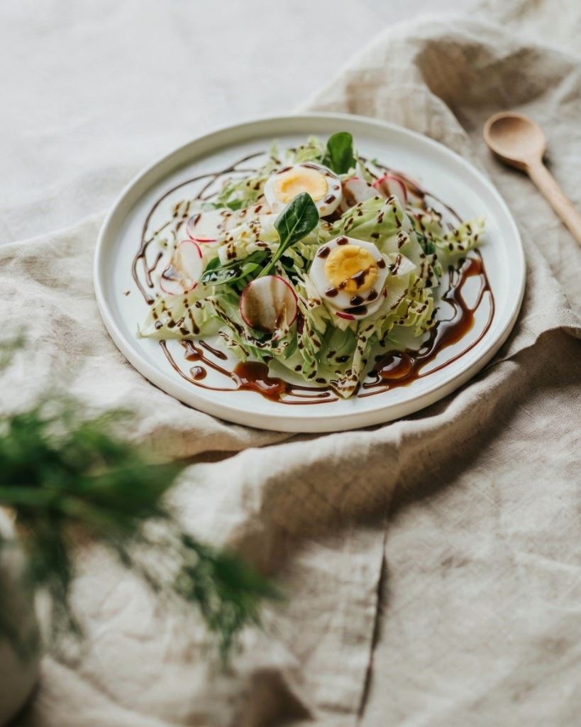 Grüner Salat mit Ei und Radieschen, abgerundet mit dunklem Kürbiskernöl